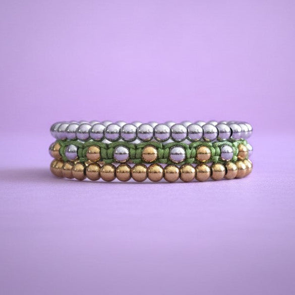 Stack of three beaded bracelets on a purple background