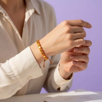 Made by Mothers Stella Aura bracelet with orange satin cord and gold stainless steel beads on a woman's wrist.